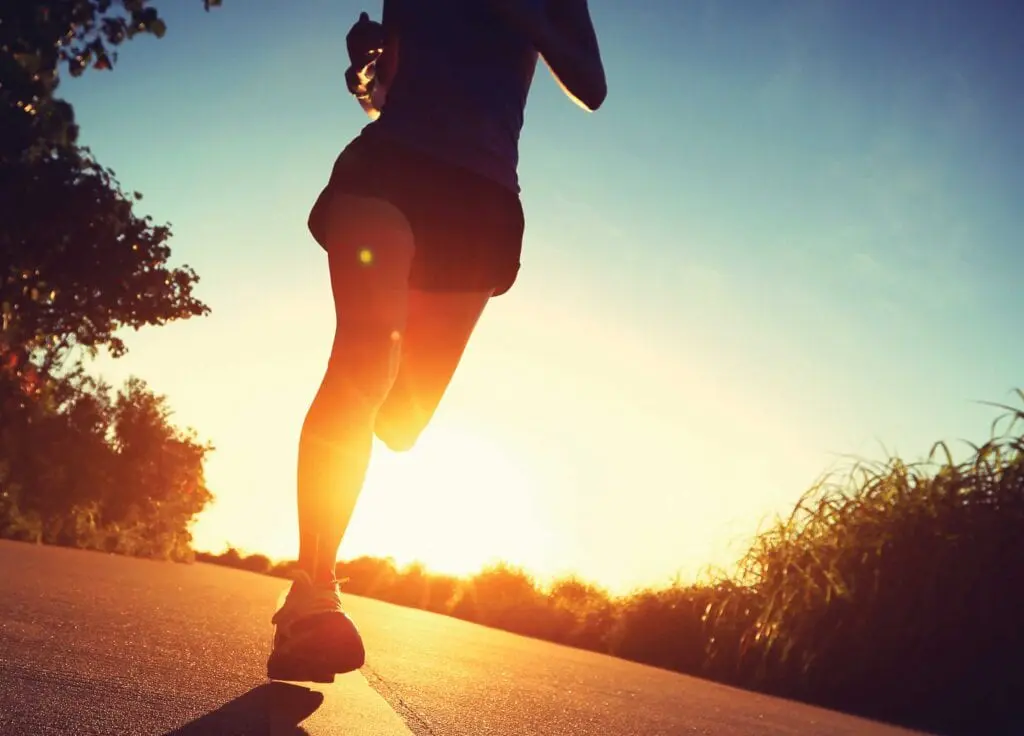 A person running on the road during sunset.