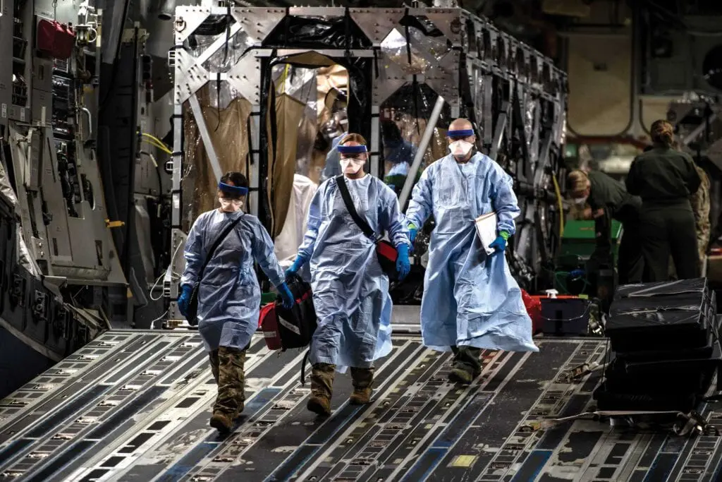 Three people in blue coats walking on a ramp.