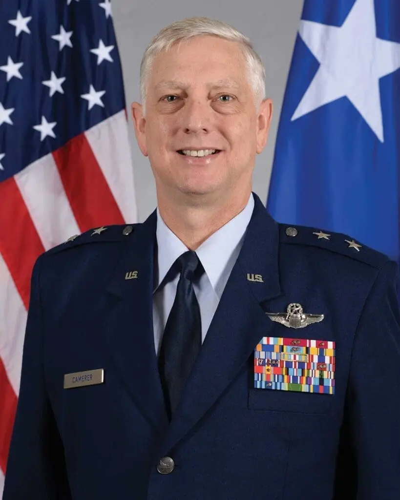 A man in military uniform standing next to flags.