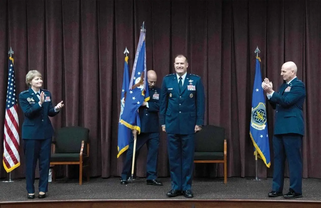 A man in uniform standing on stage with two other men.