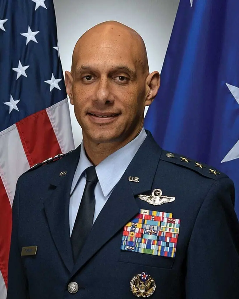 A man in military uniform standing next to flags.