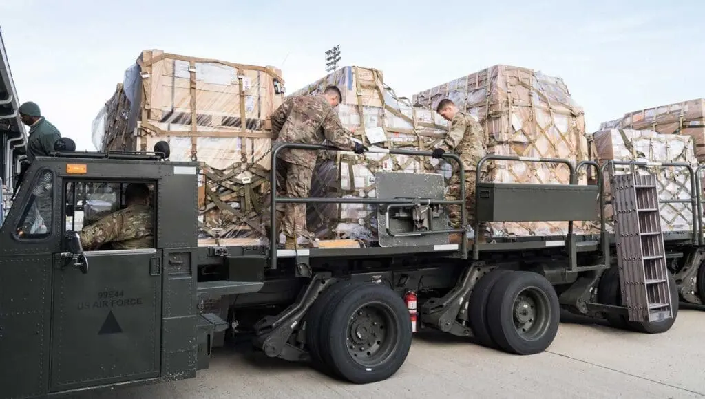A truck with two men standing on the back of it.
