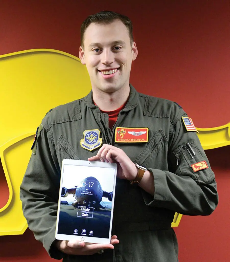 A man holding an ipad in front of a yellow elephant.