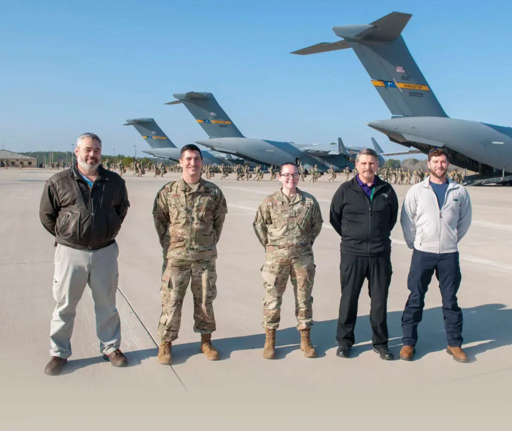 Five men standing in front of a line of planes.