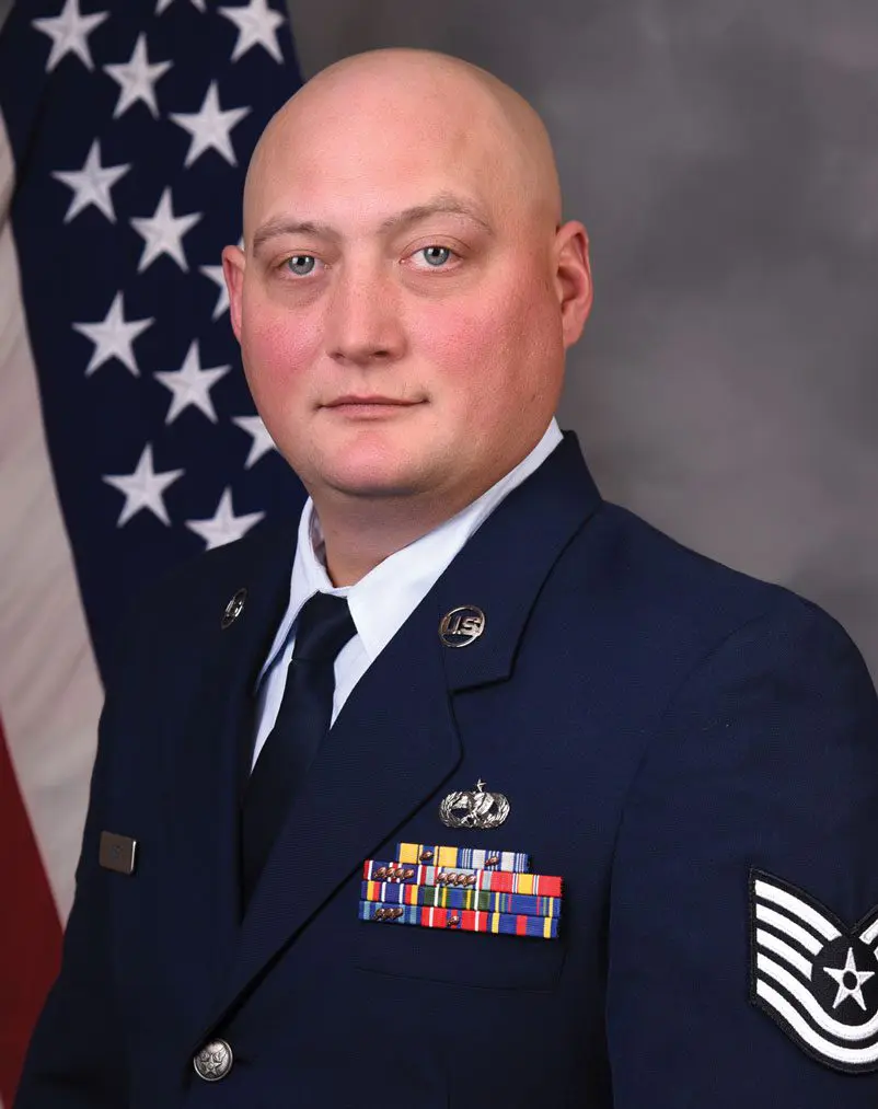 A man in uniform with an american flag behind him.
