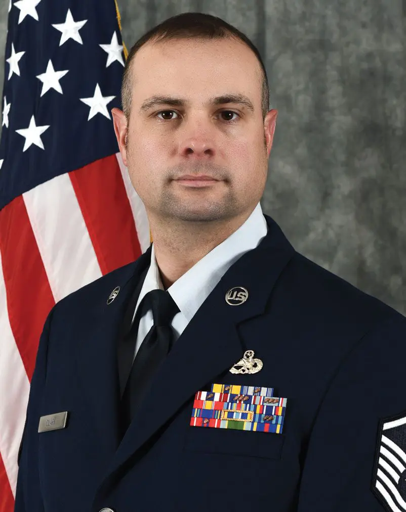 A man in uniform with an american flag behind him.