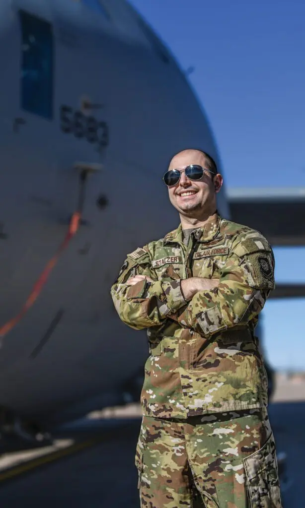 A man in military fatigues standing next to an airplane.