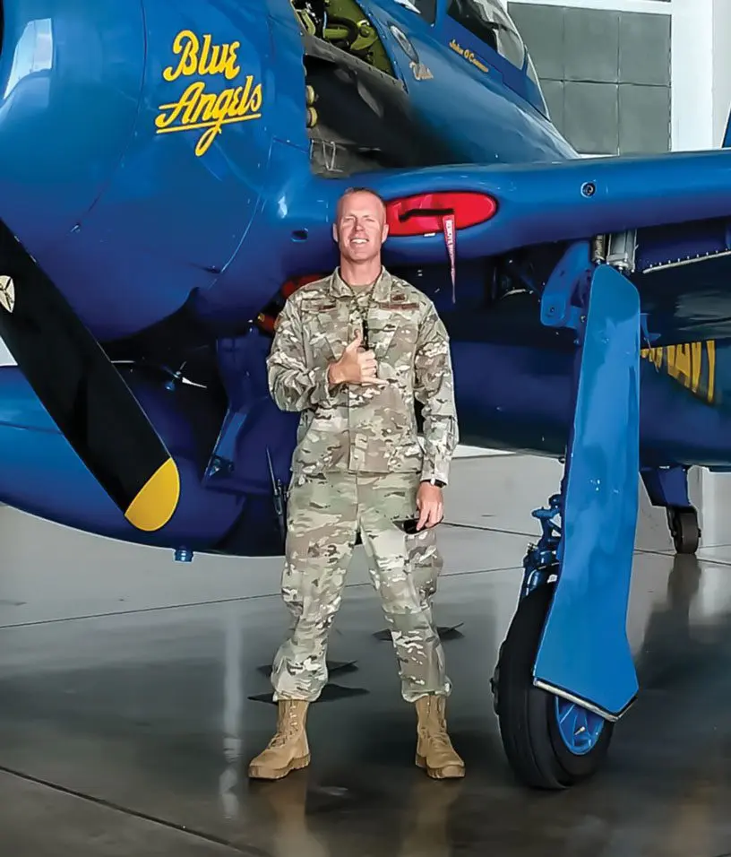 A man in military uniform standing next to an airplane.