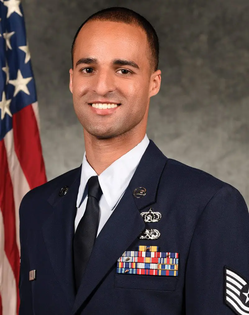 A man in uniform standing next to an american flag.