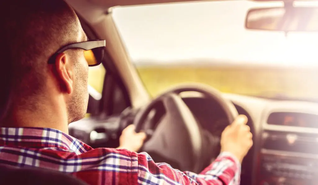 A man driving in his car with glasses on.