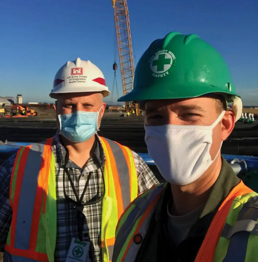 Two men wearing hard hats and masks standing next to each other.