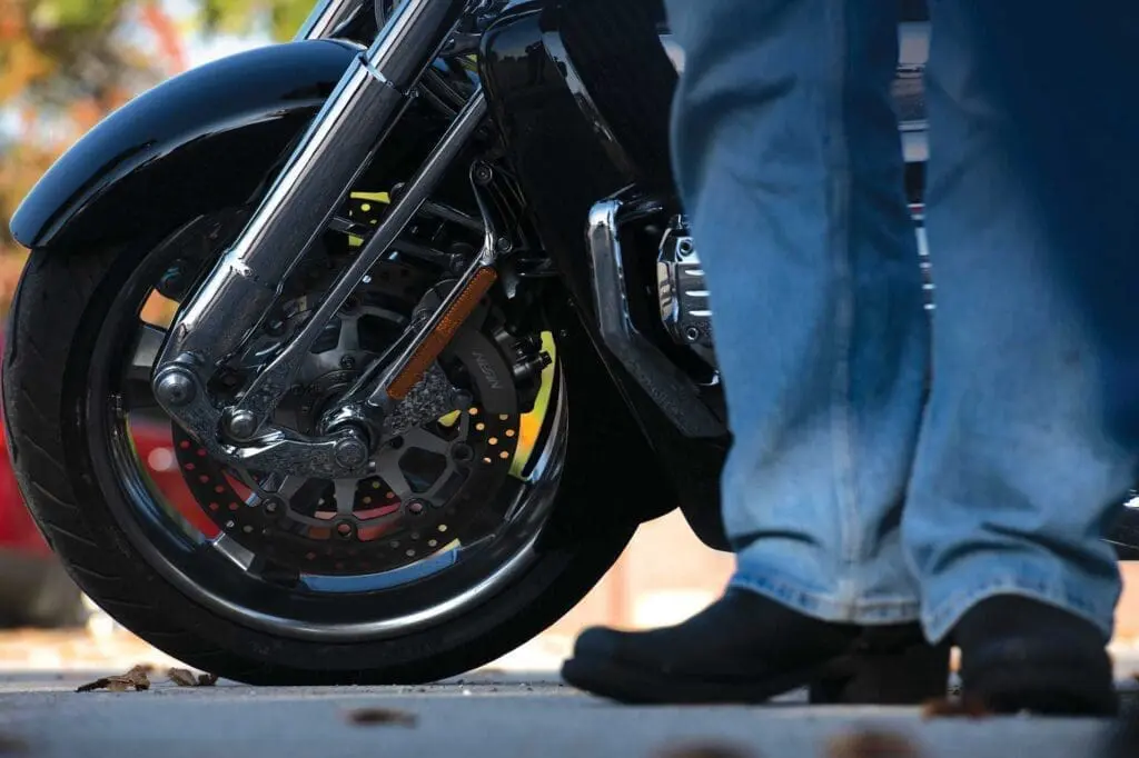 A person standing next to a motorcycle on the street.