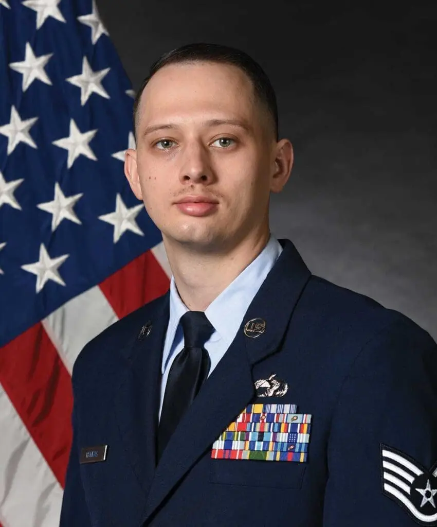 A man in uniform standing next to an american flag.