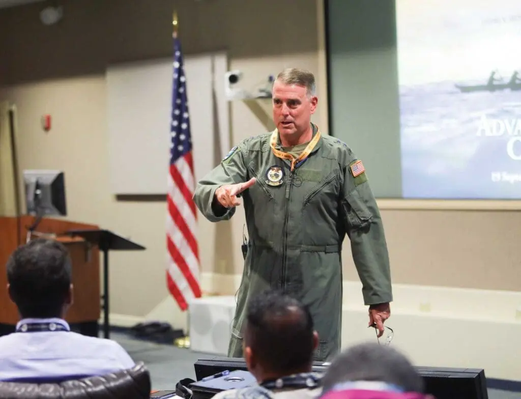 A man in an air force uniform pointing to the sky.