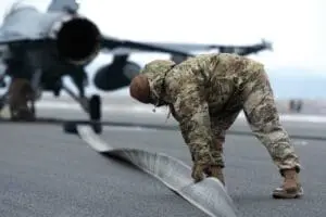 A soldier is bending over to inspect the landing gear.