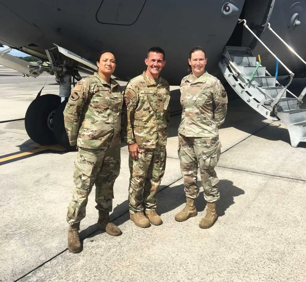 Three soldiers standing in front of a plane.