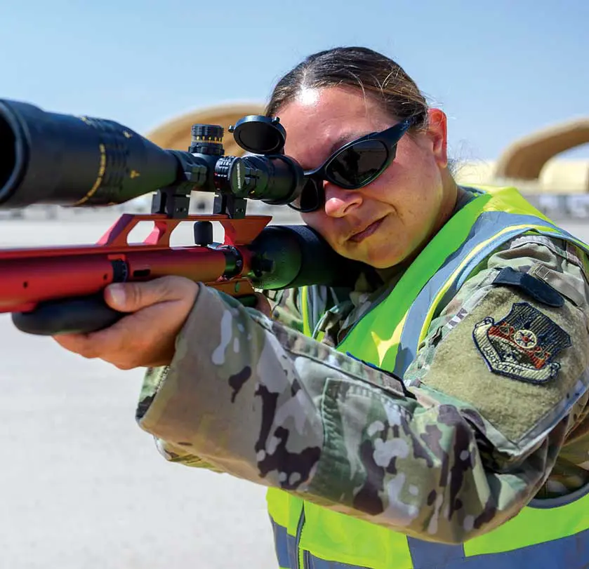 A man in yellow vest holding a rifle.