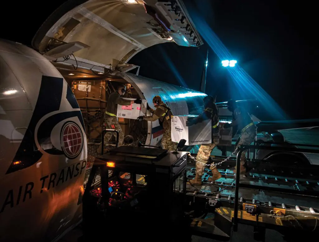 A man standing in front of an airplane at night.