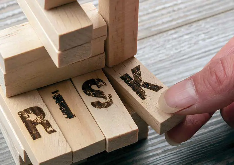 A person is playing with wooden blocks that spell out " risk ".