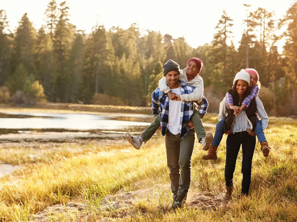 A group of people walking in the grass near water.