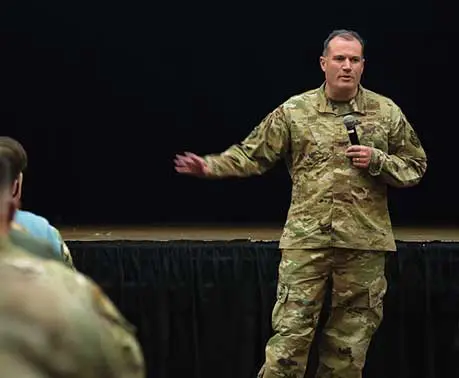 A man in military fatigues is holding a microphone.