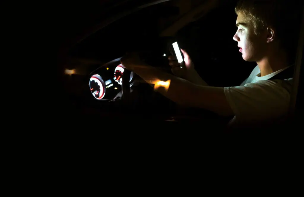 A person in the dark holding up their phone.