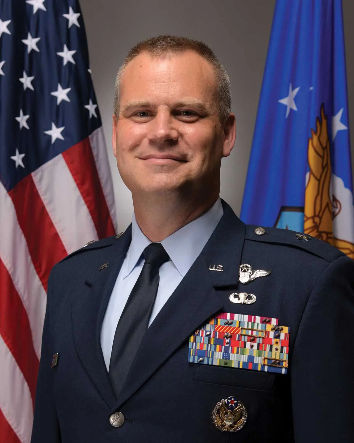 A man in military uniform standing next to flags.
