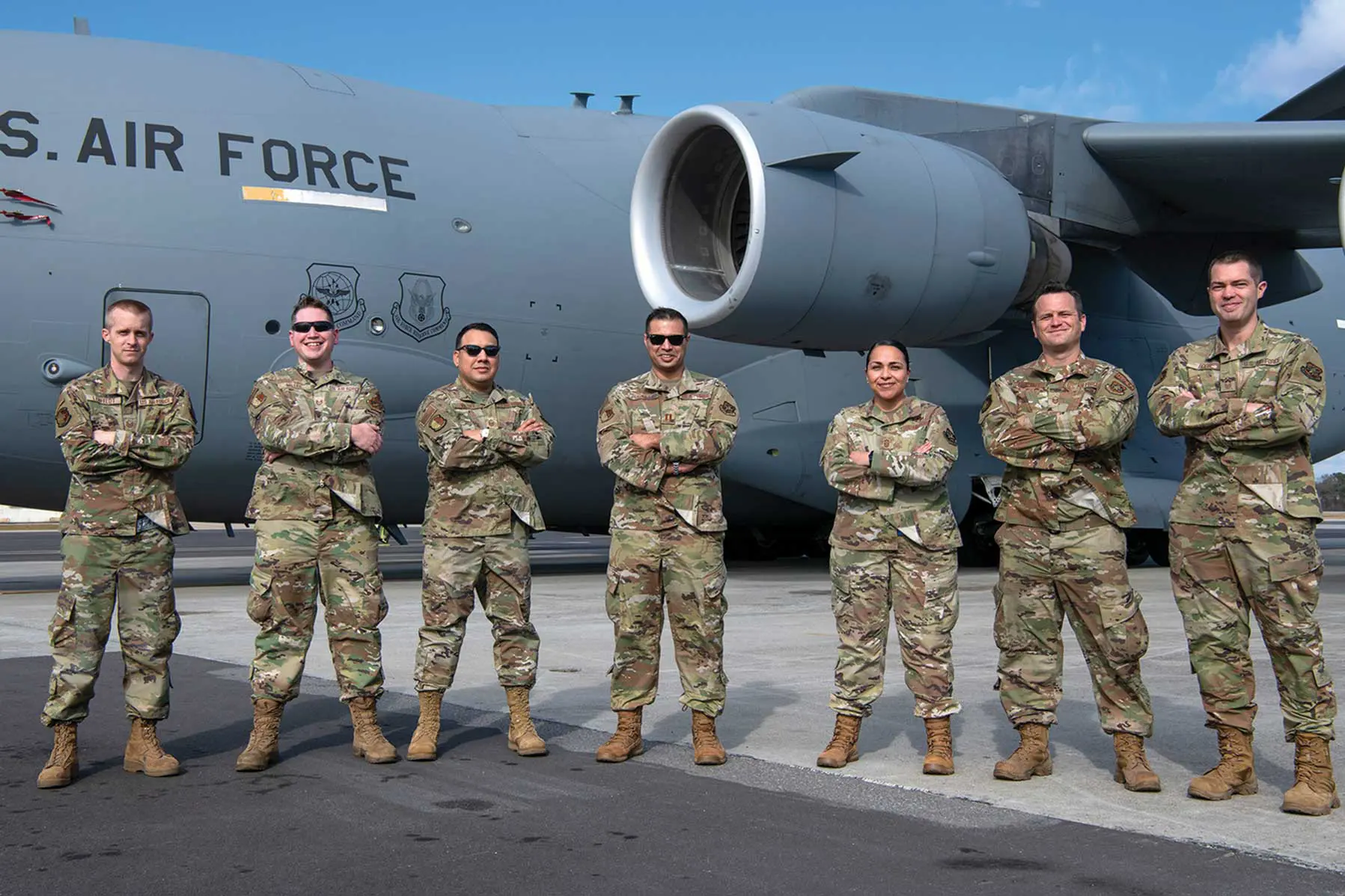 A group of soldiers standing in front of an airplane.