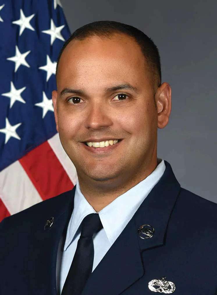 A man in uniform with an american flag behind him.