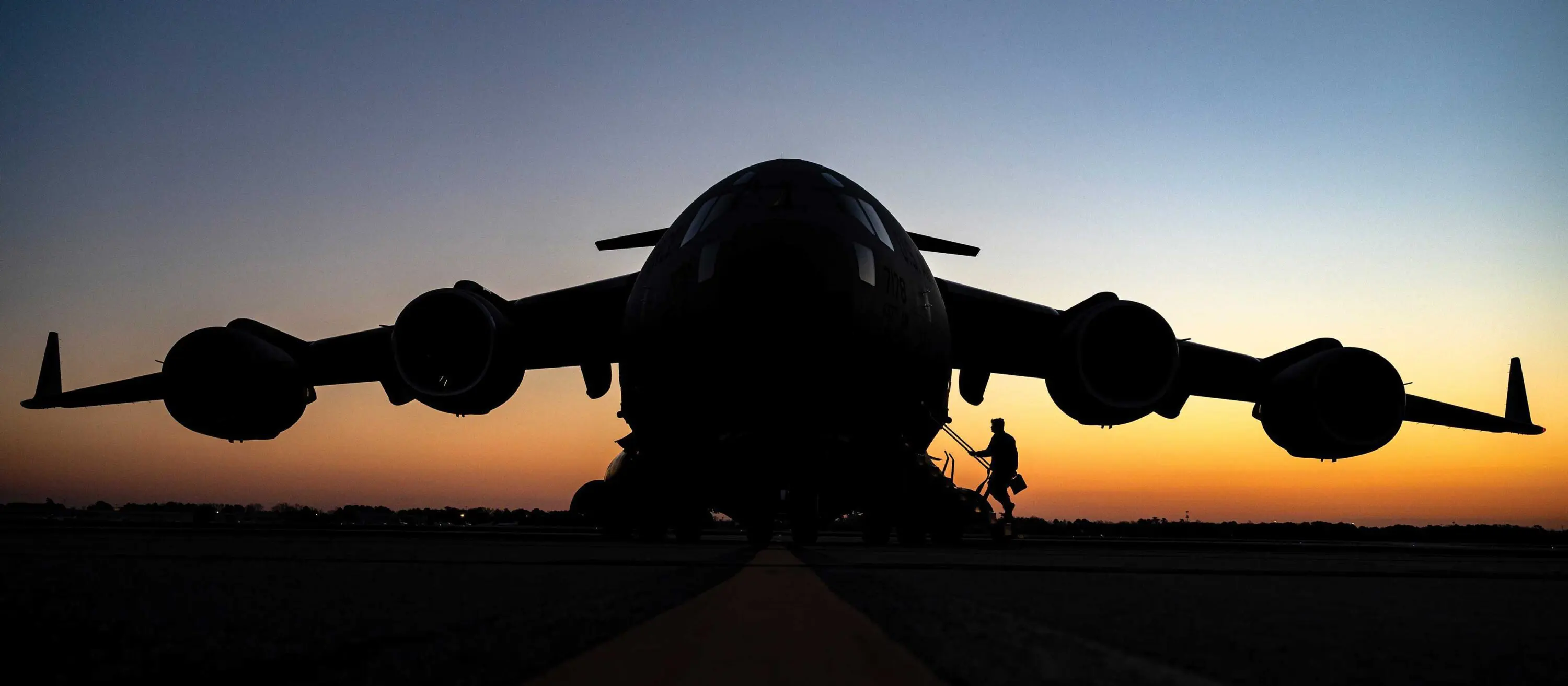 A person walking on the ground near an airplane.