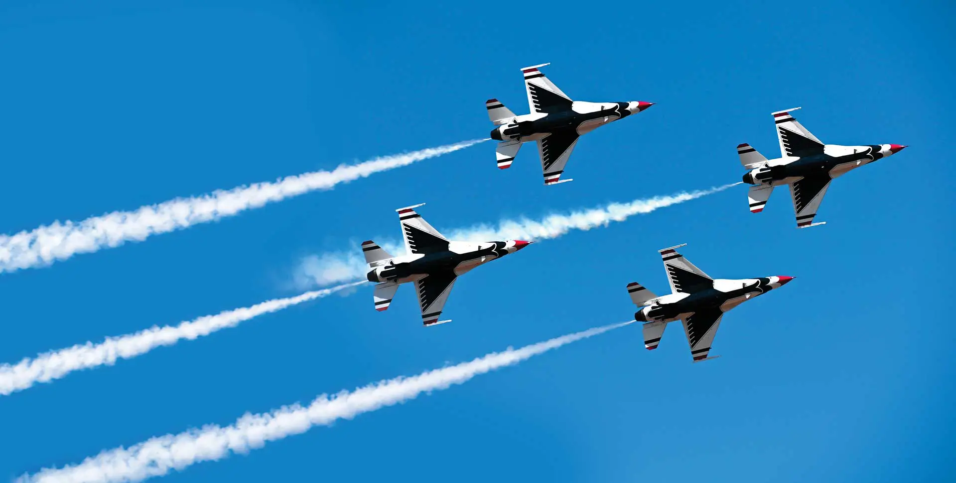 Three jets flying in formation with smoke trailing behind them.