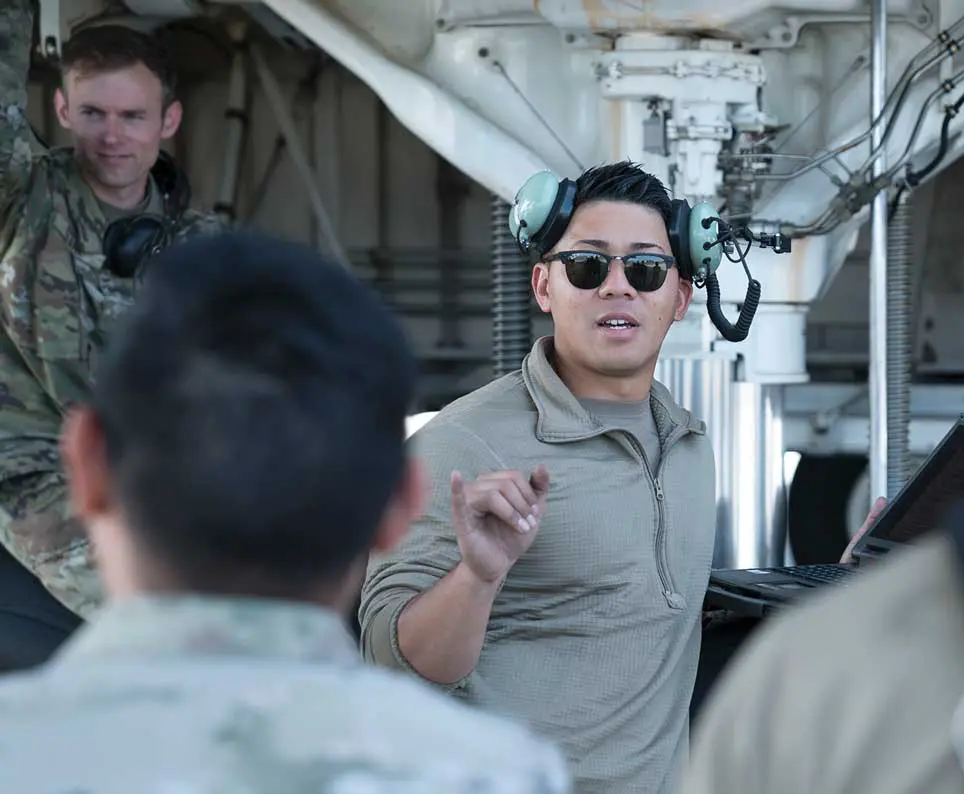 A man in sunglasses and headphones talking to some people.
