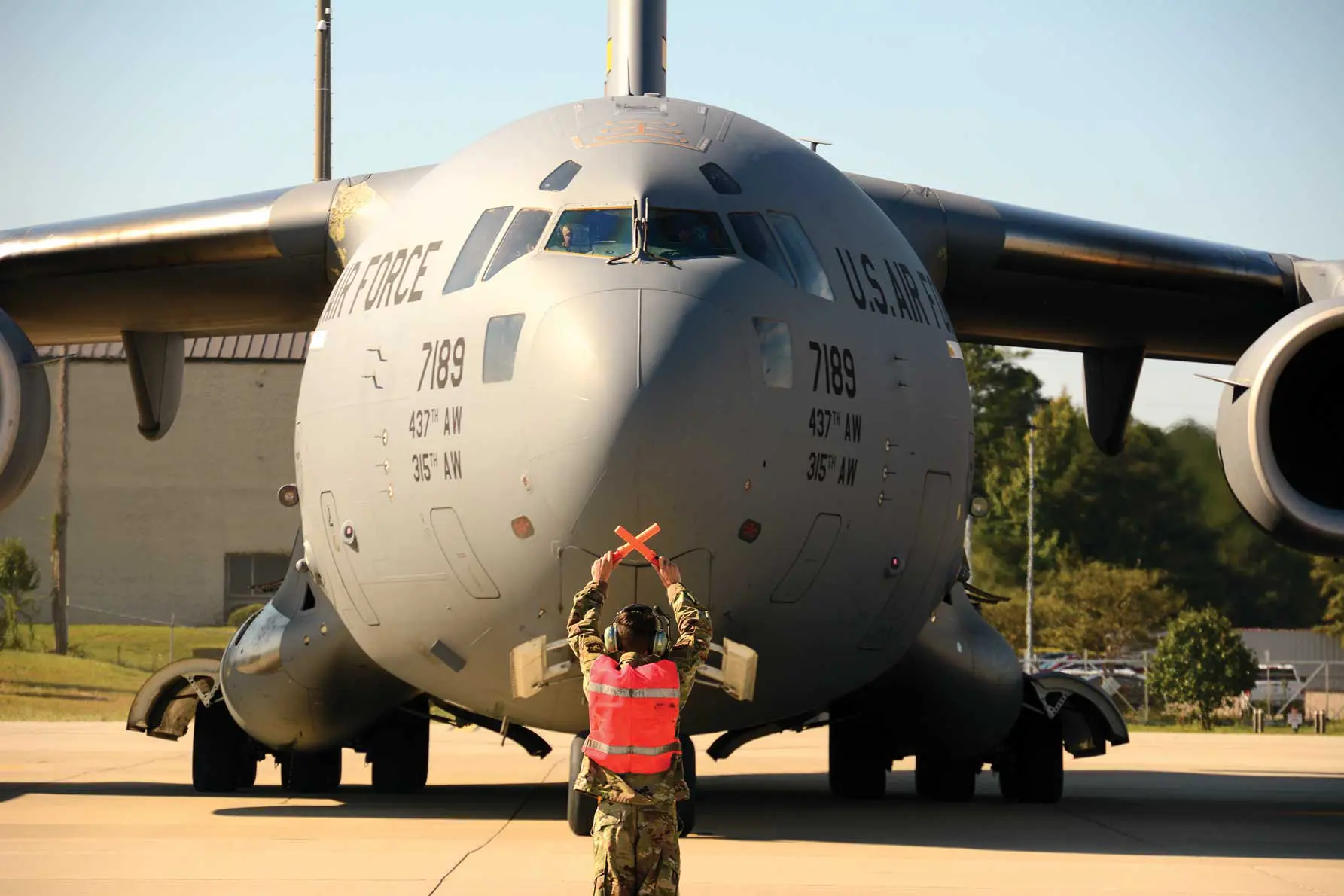 A man in camouflage jacket standing next to an airplane.