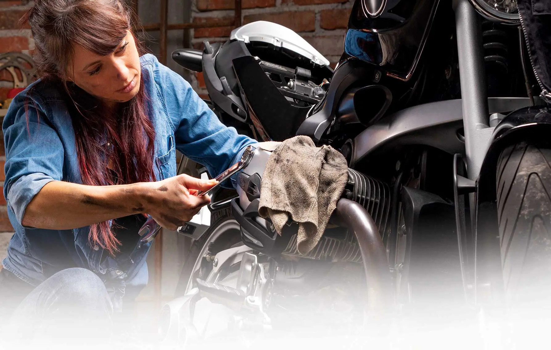 A woman is working on a motorcycle