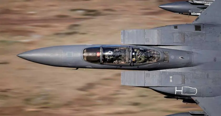 A fighter jet flying through the air on a cloudy day.