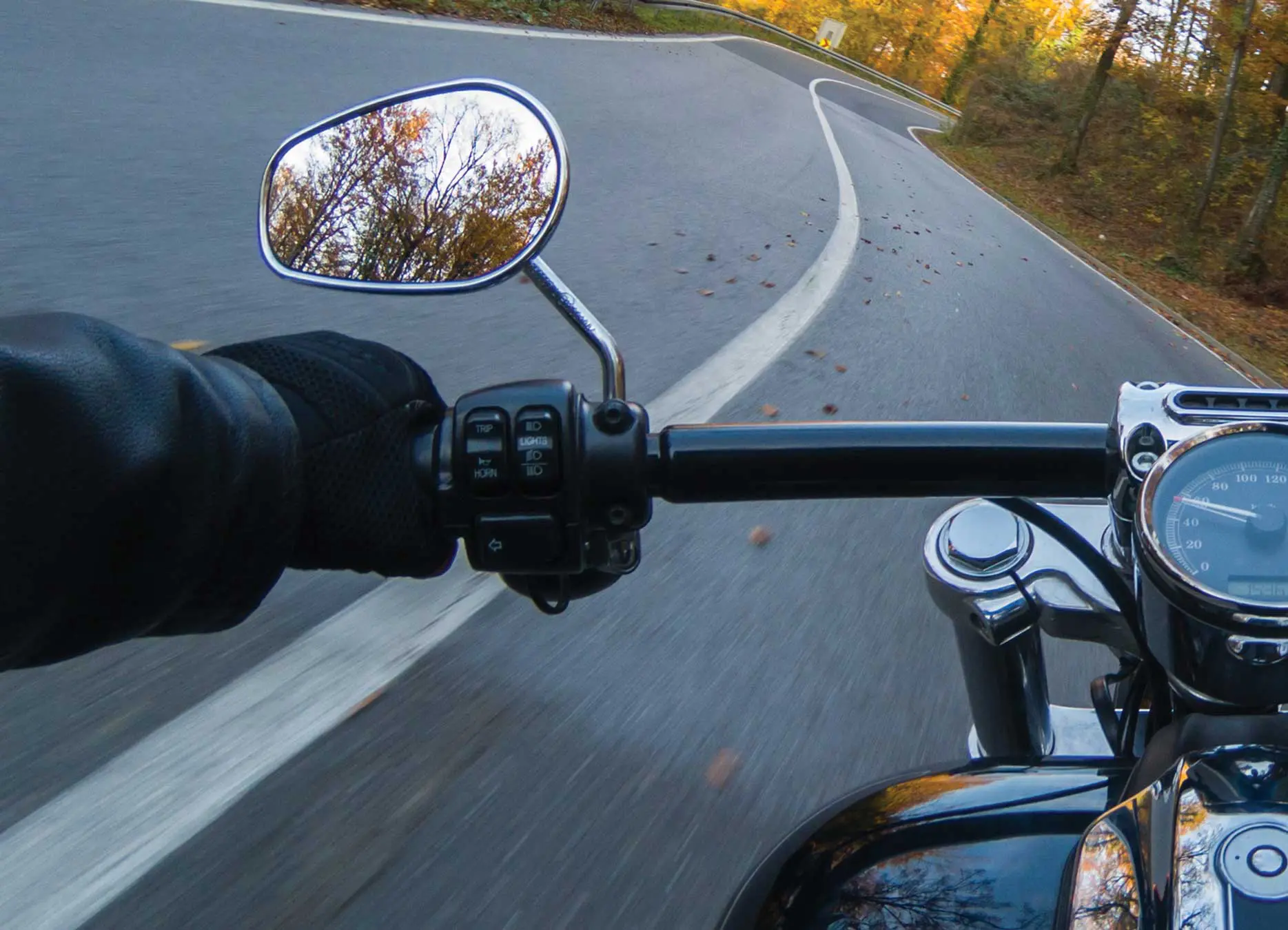 A motorcycle rider 's view of the side mirror and handlebar.