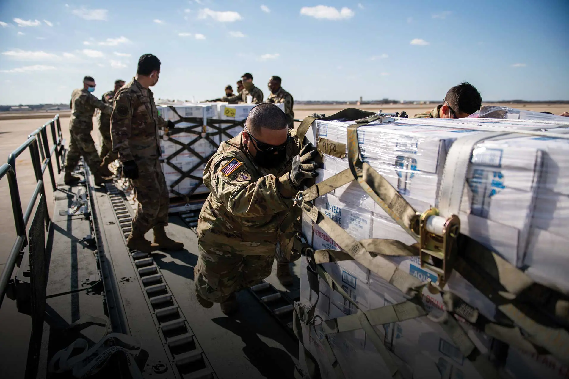 A group of people in military uniforms unloading boxes.