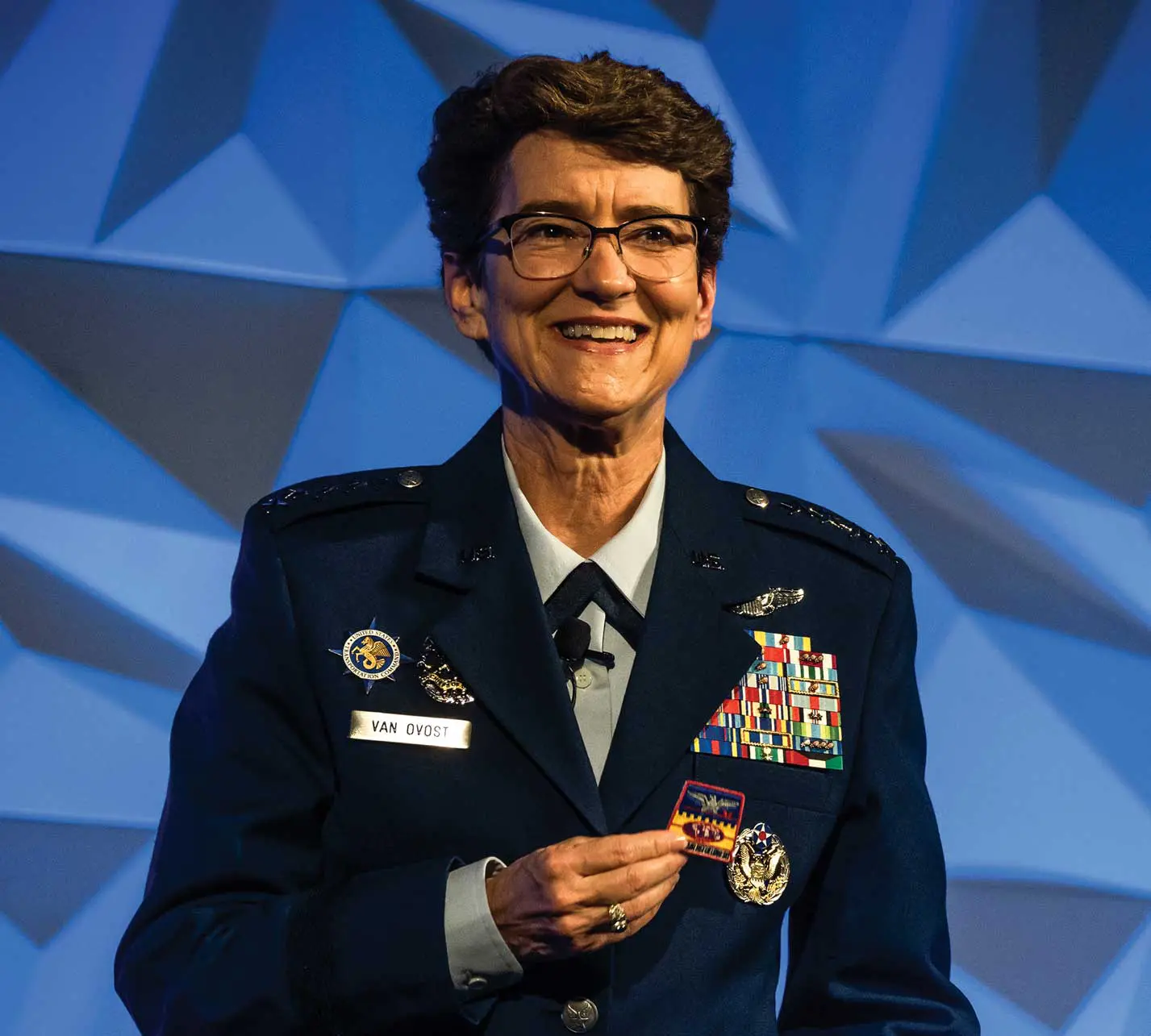 A woman in uniform smiles while holding her cell phone.