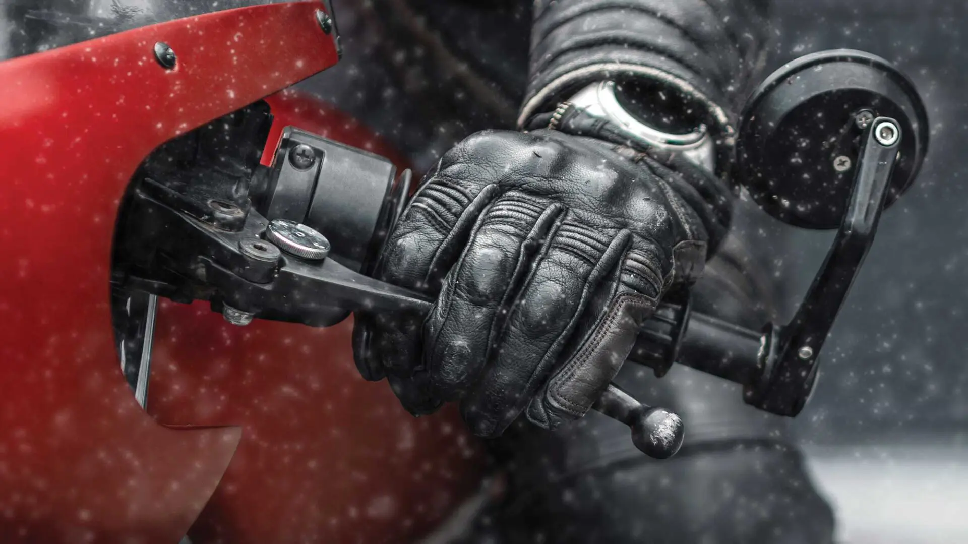 A person wearing gloves and holding onto the handle of a motorcycle.