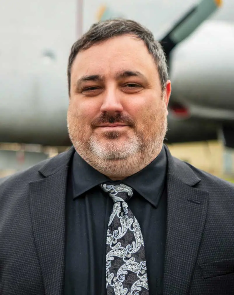 A man in a suit and tie standing next to an airplane.