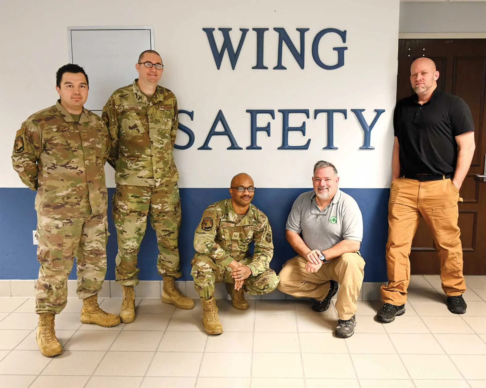 A group of men standing in front of wing safety sign.