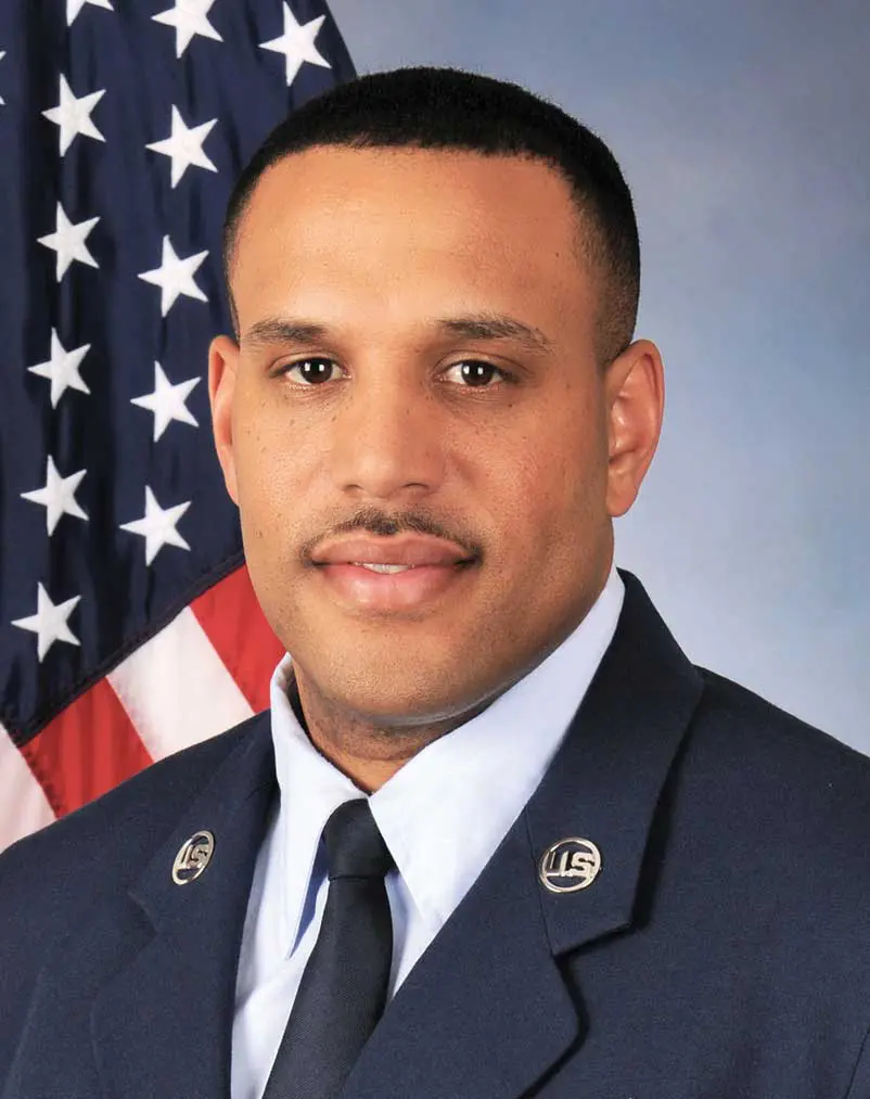 A man in uniform with an american flag behind him.