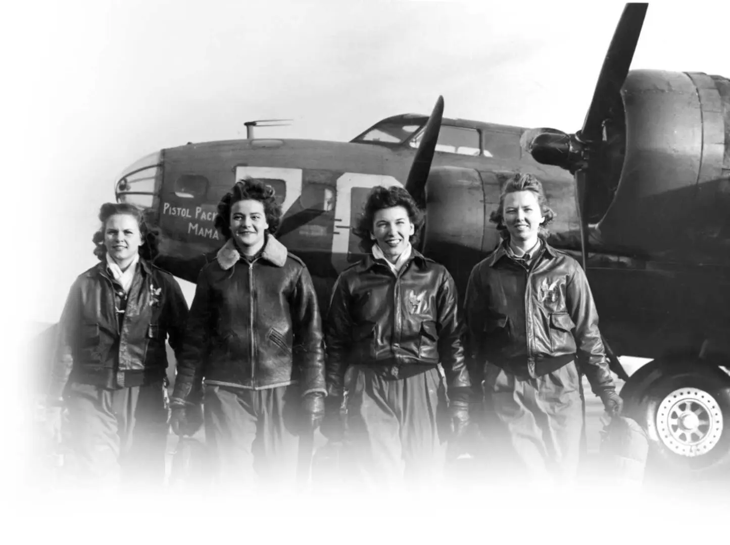A group of women standing in front of an airplane.