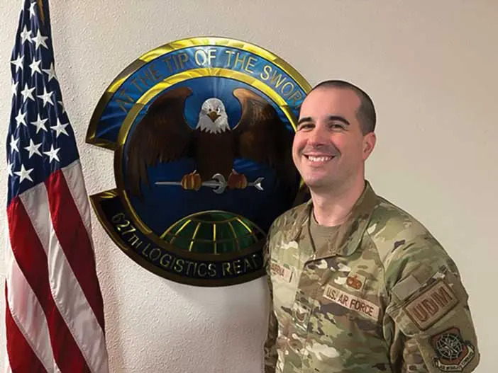 A man in military fatigues standing next to an eagle.