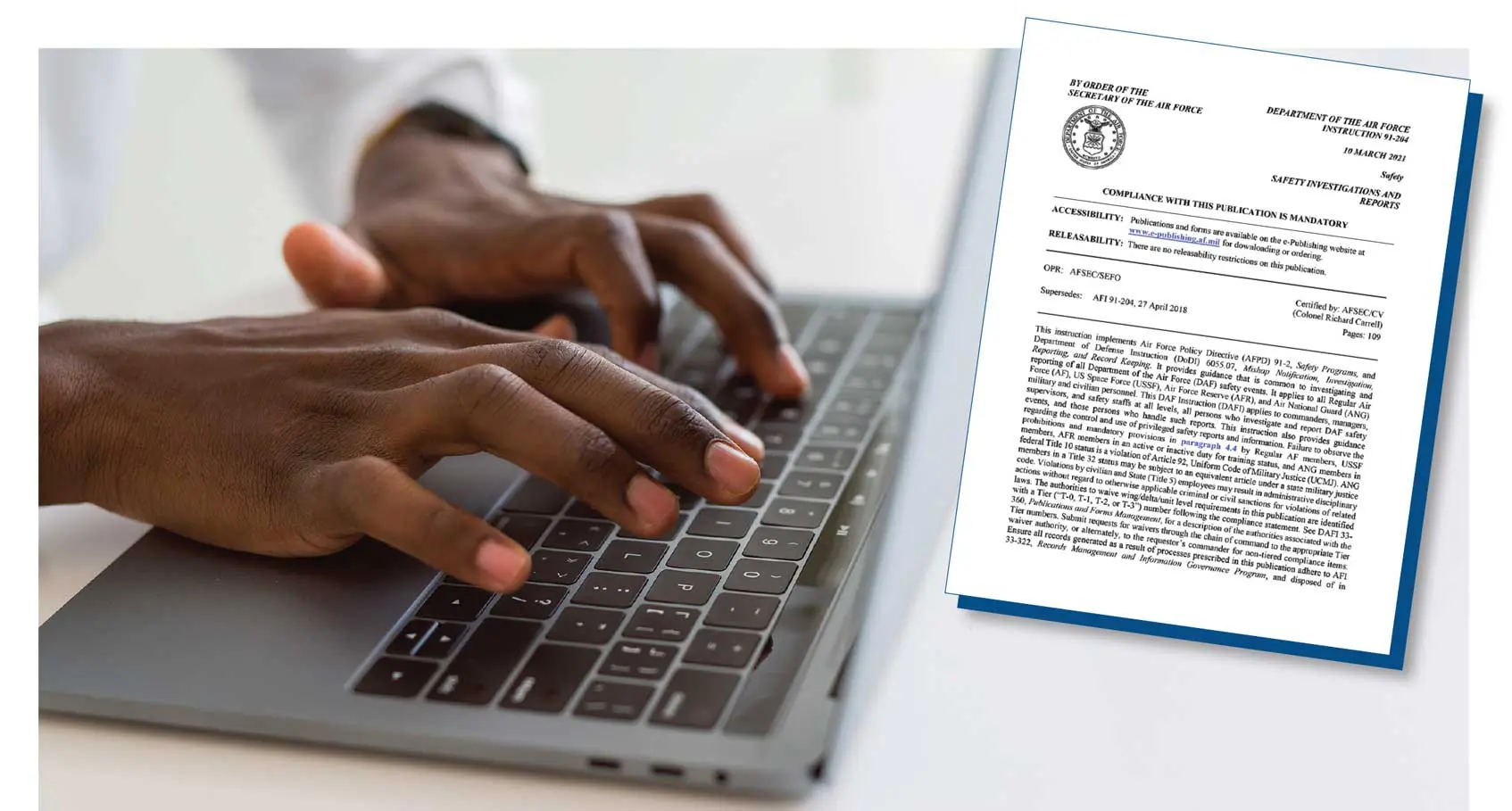 A person typing on a laptop with papers in front of them.