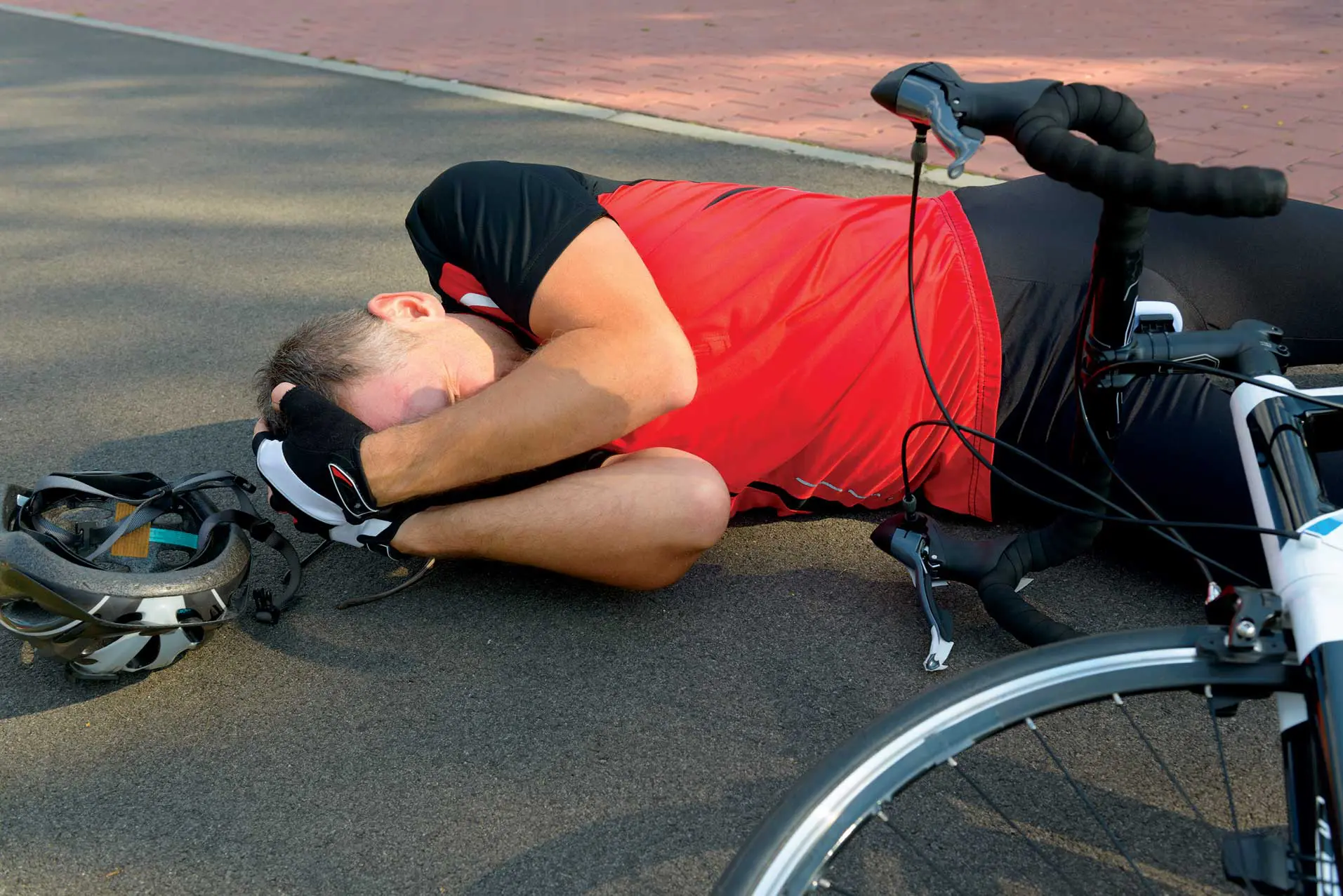 A man laying on the ground next to his bicycle.