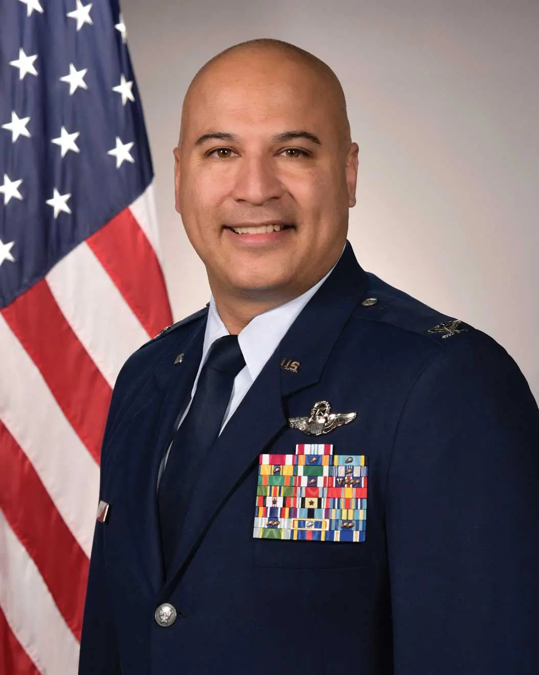 A man in uniform standing next to an american flag.