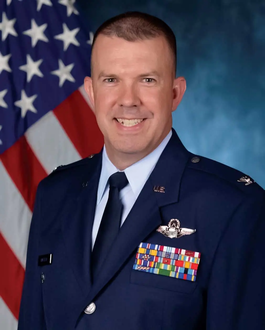 A man in uniform with an american flag behind him.