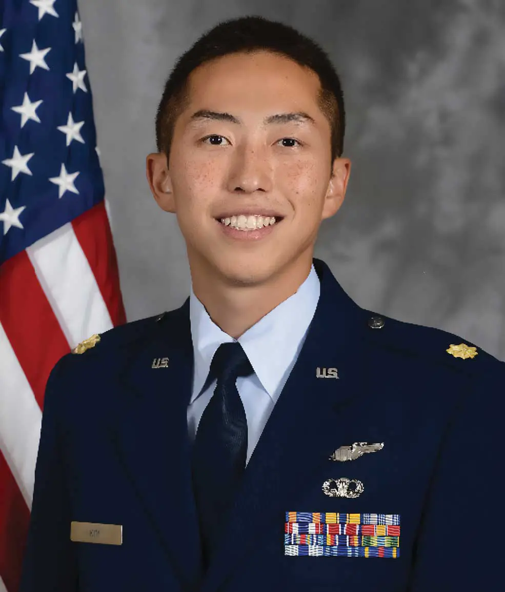 A man in military uniform standing next to an american flag.