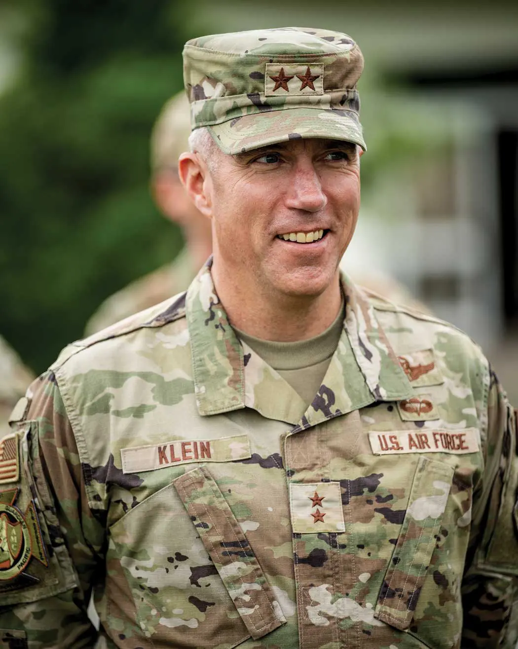 A man in military fatigues and hat standing next to other men.
